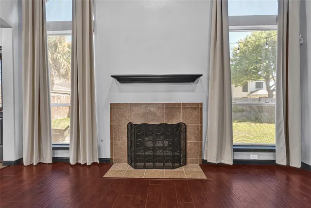 an empty room with wooden floor fireplace and windows