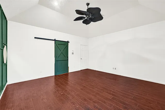 an empty room with wooden floor ceiling fan and window