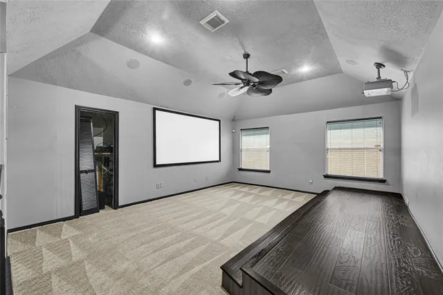 an empty room with windows and ceiling fan