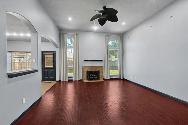 a view of an empty room with wooden floor and a fireplace