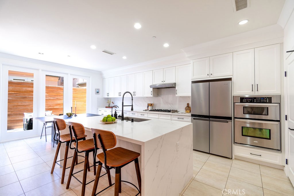 58 Cipresso Irvine, CA 92618 - Photo 7 of 34 a kitchen with a refrigerator a stove a dining table and chairs