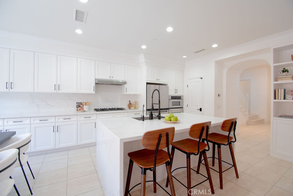 58 Cipresso Irvine, CA 92618 - Photo 8 of 34 a kitchen with stainless steel appliances granite countertop white cabinets and chairs