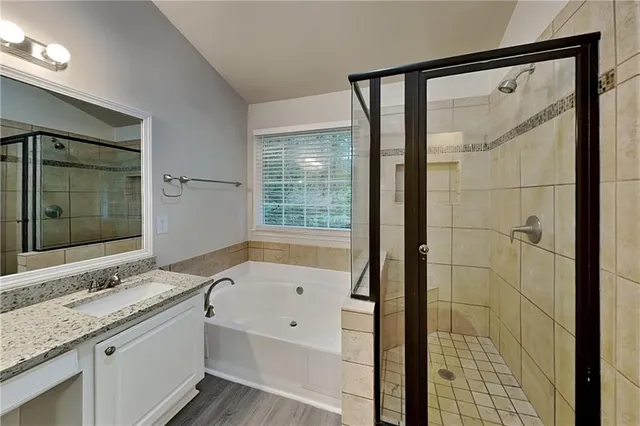a bathroom with a granite countertop sink a mirror and a bathtub