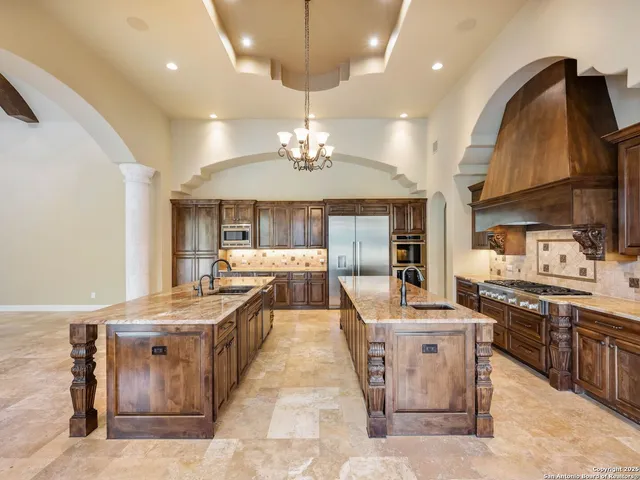 a large kitchen with stainless steel appliances kitchen island granite countertop a large stove a sink dishwasher and white cabinets with wooden floor