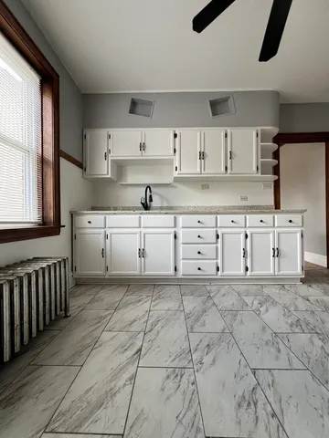 a kitchen with white cabinets a sink a stove and a window