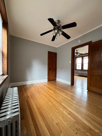 a view of empty room with wooden floor and fan