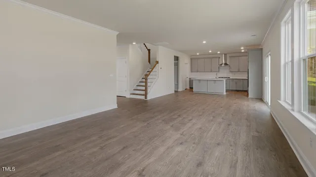 a view of an empty room with a window and kitchen view