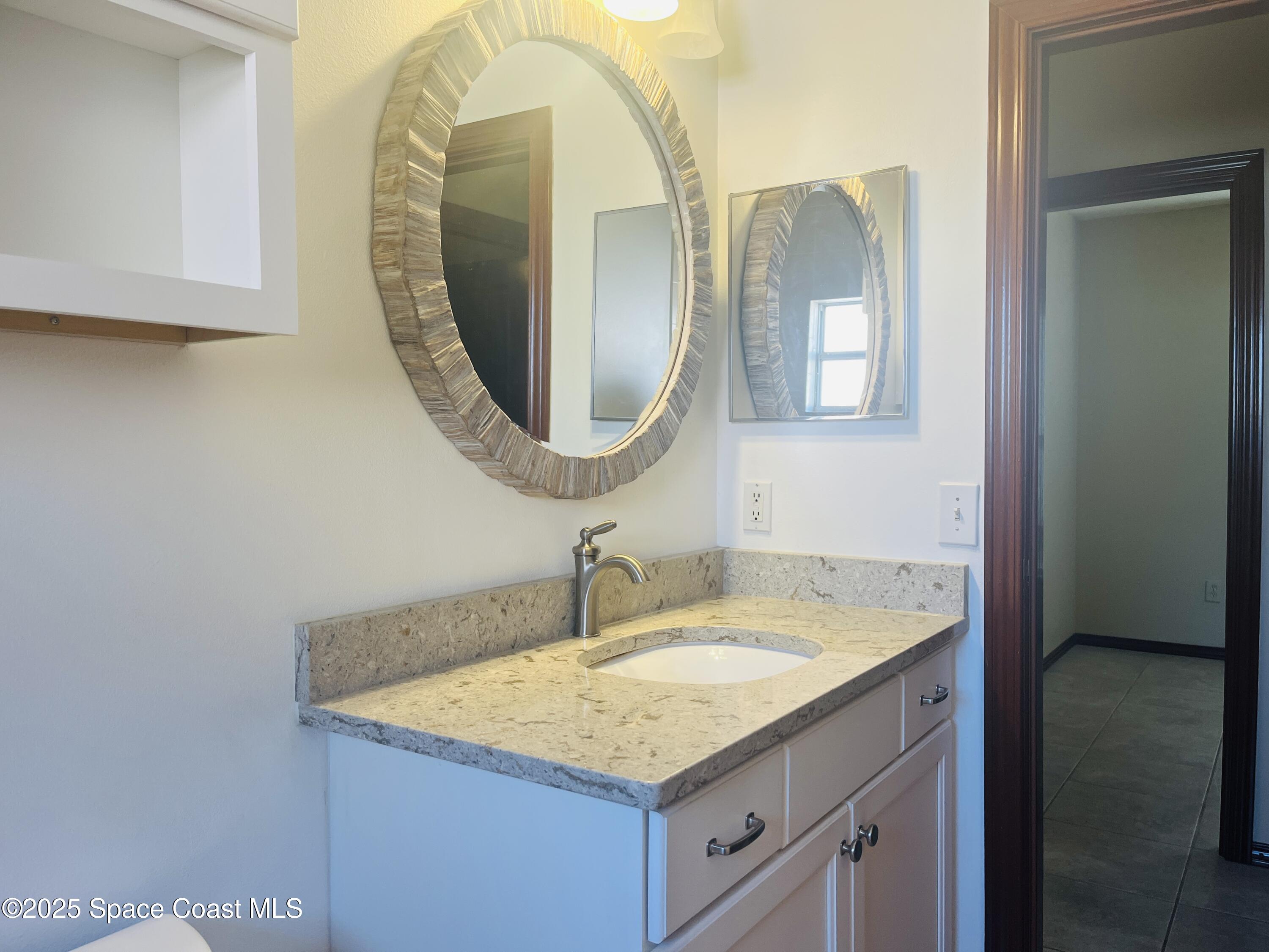 3 Florida Avenue, Unit B Cocoa, FL 32922 - Photo 9 of 10 a bathroom with a granite countertop sink and a mirror