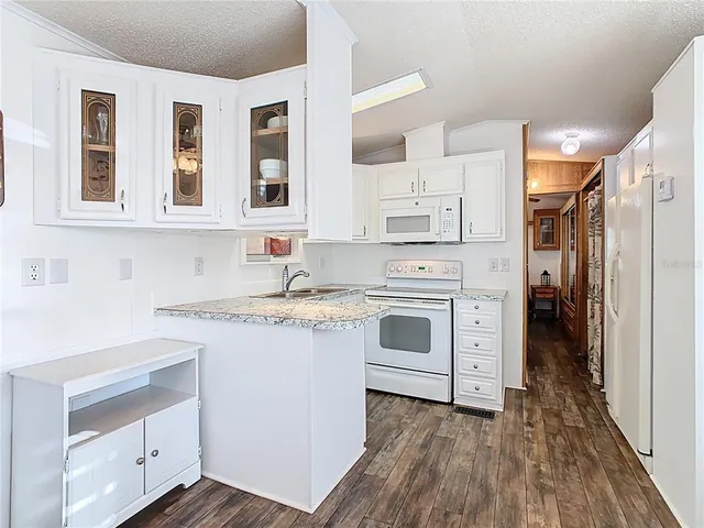 a kitchen with granite countertop white cabinets and white appliances