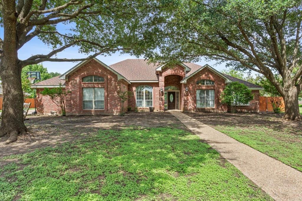 View of front of property featuring brick siding and roof with shingles