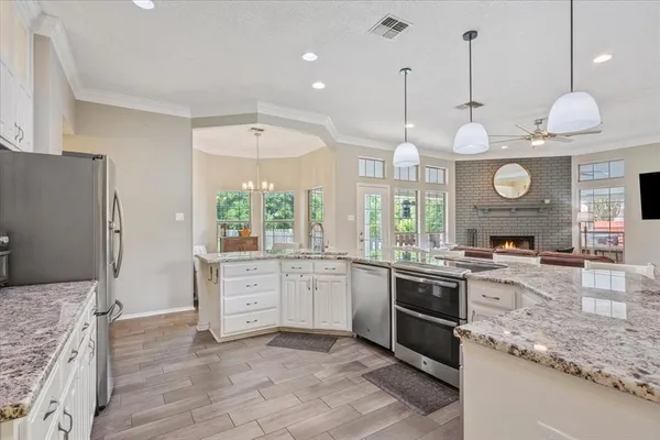 a large kitchen with granite countertop a sink cabinets and stainless steel appliances
