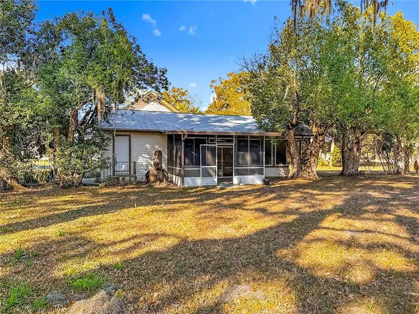 a view of a white house with a large pool and a lawn chairs under an umbrella