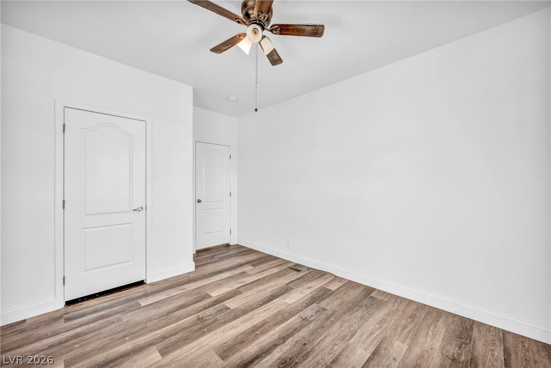 225 California Street Searchlight, NV 89046 - Photo 33 of 64 A warm ceiling fan casts a soft glow over rich hardwood-style flooring in this versatile space.