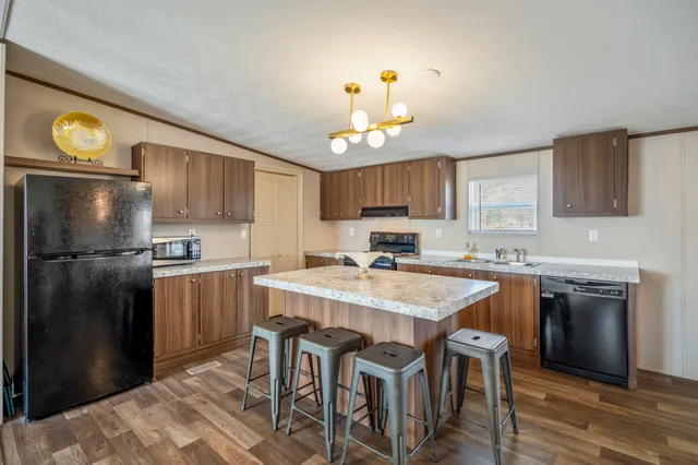 a kitchen with a chandelier a sink cabinets and stainless steel appliances