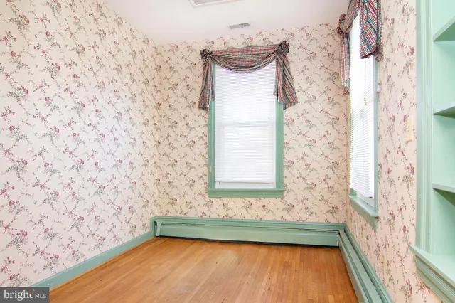 a view of an empty room with window and wooden floor