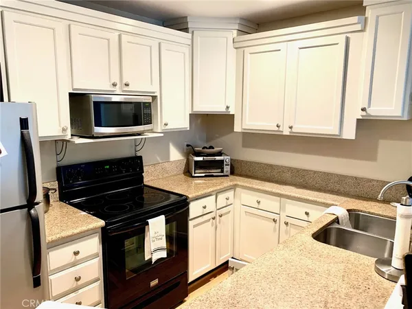 a kitchen with granite countertop white cabinets and black appliances