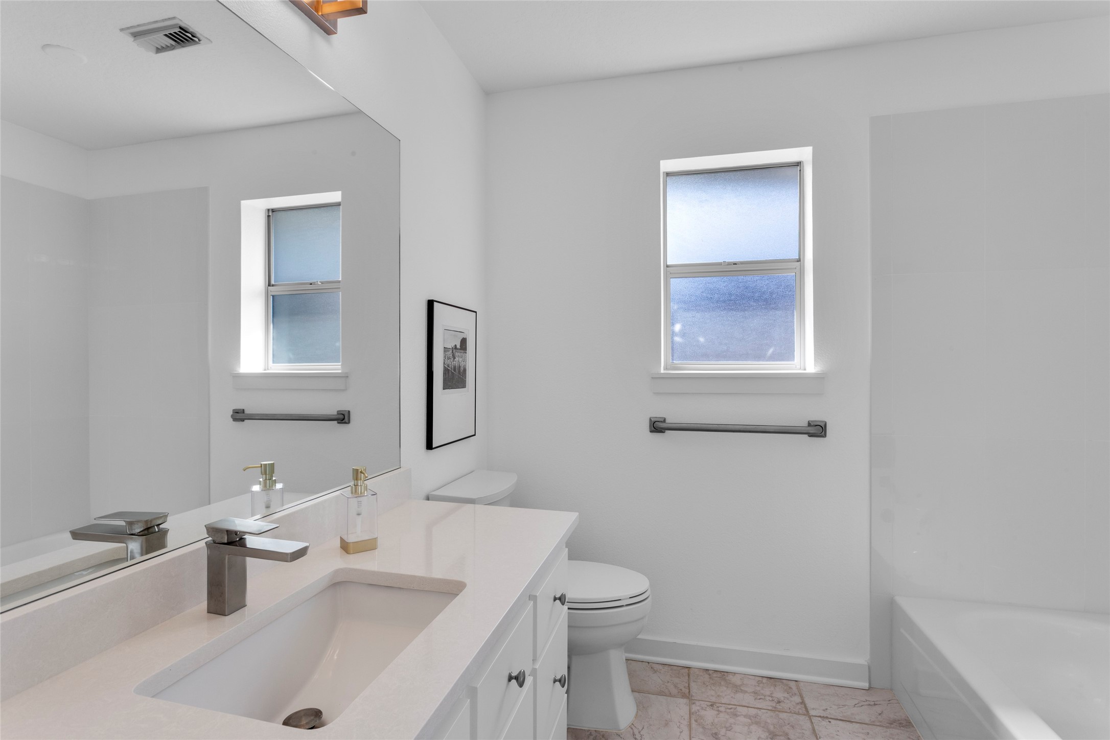 67 Harbor Lane Kemah, TX 77565 - Photo 22 of 47 Another updated modern secondary bathroom, It's bright with a large mirror, sleek white countertop with a sink, and a bathtub. There are two frosted windows allowing natural light.