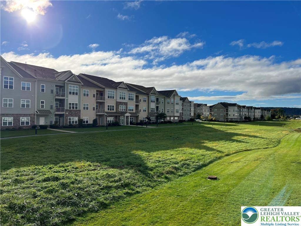2356 Raya Way Easton, PA 18045 - Photo 27 of 28 A spacious green lawn sits adjacent to multi-story residential buildings under a bright sky.