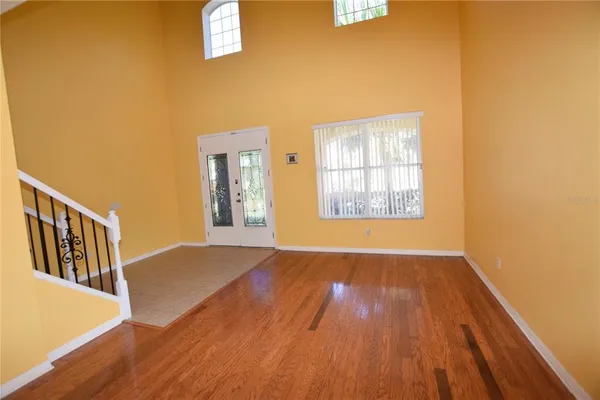 a view of an empty room with window and wooden floor