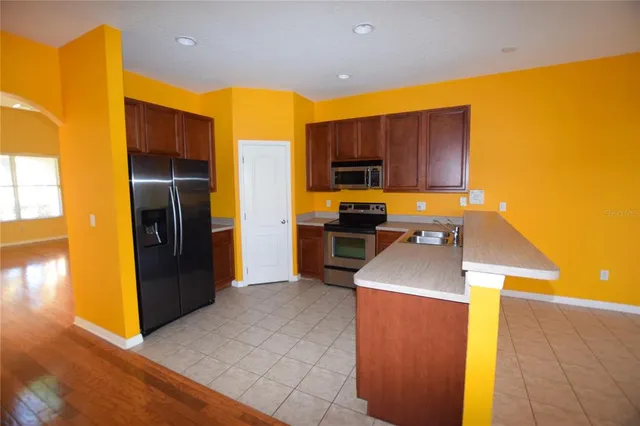 a kitchen with stainless steel appliances granite countertop a refrigerator a stove and a sink