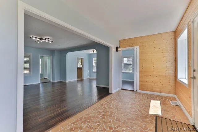 an empty room with wooden floor chandelier and windows