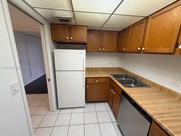 a kitchen with a refrigerator a stove top oven cabinetry and a sink