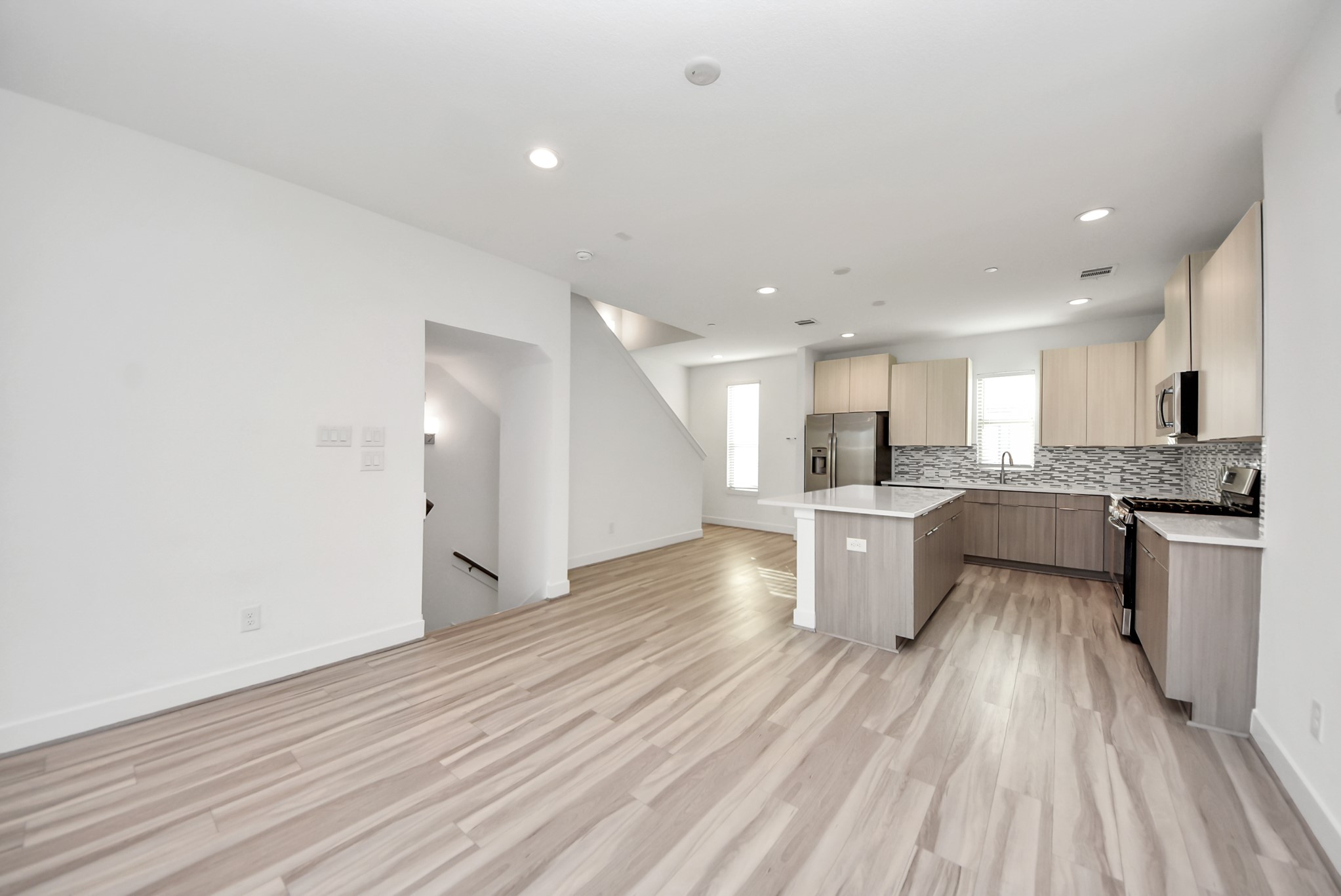 18716 Centro Main Street Conroe, TX 77385 - Photo 27 of 50 Expansive living room seamlessly connected to the kitchen, featuring high ceilings, modern lighting, and an open layout that maximizes flow and functionality.