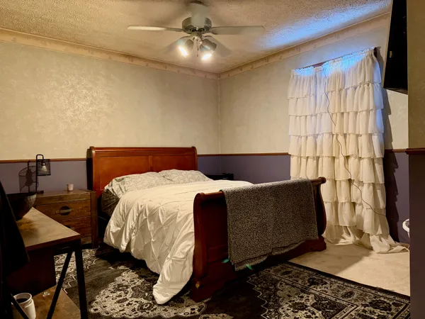 a bed sitting in a bedroom next to a window with a flat screen tv and dresser