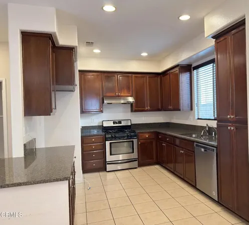 a kitchen with stainless steel appliances granite countertop a stove a sink and a microwave