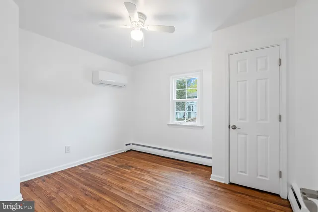 an empty room with wooden floor chandelier fan and windows