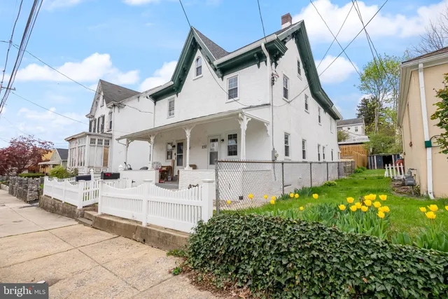 a view of a white house with a large windows and a yard with plants