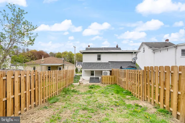 a view of a house with wooden fence next to a yard