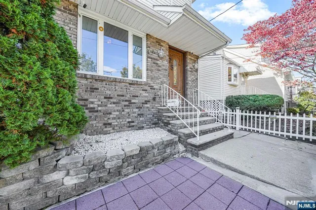 a view of a brick house with large windows and a small yard