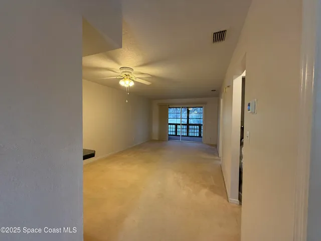 a view of a room with a ceiling fan and window