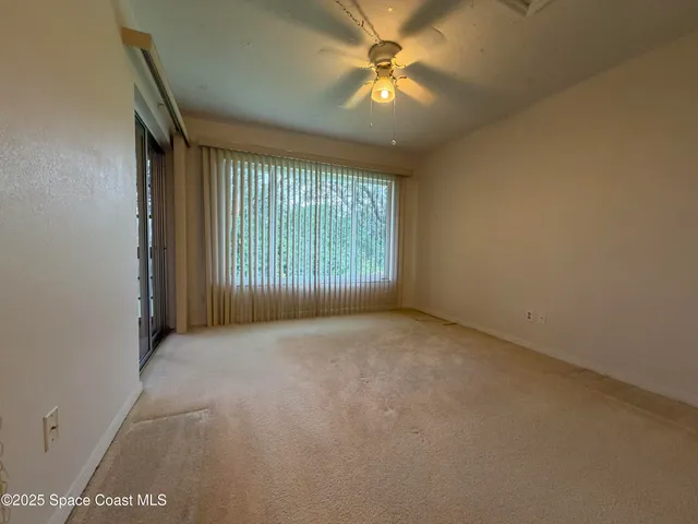 an empty room with windows and fan