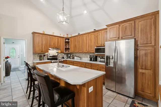 a kitchen with granite countertop a refrigerator a stove a sink dishwasher a dining table and chairs with wooden floor