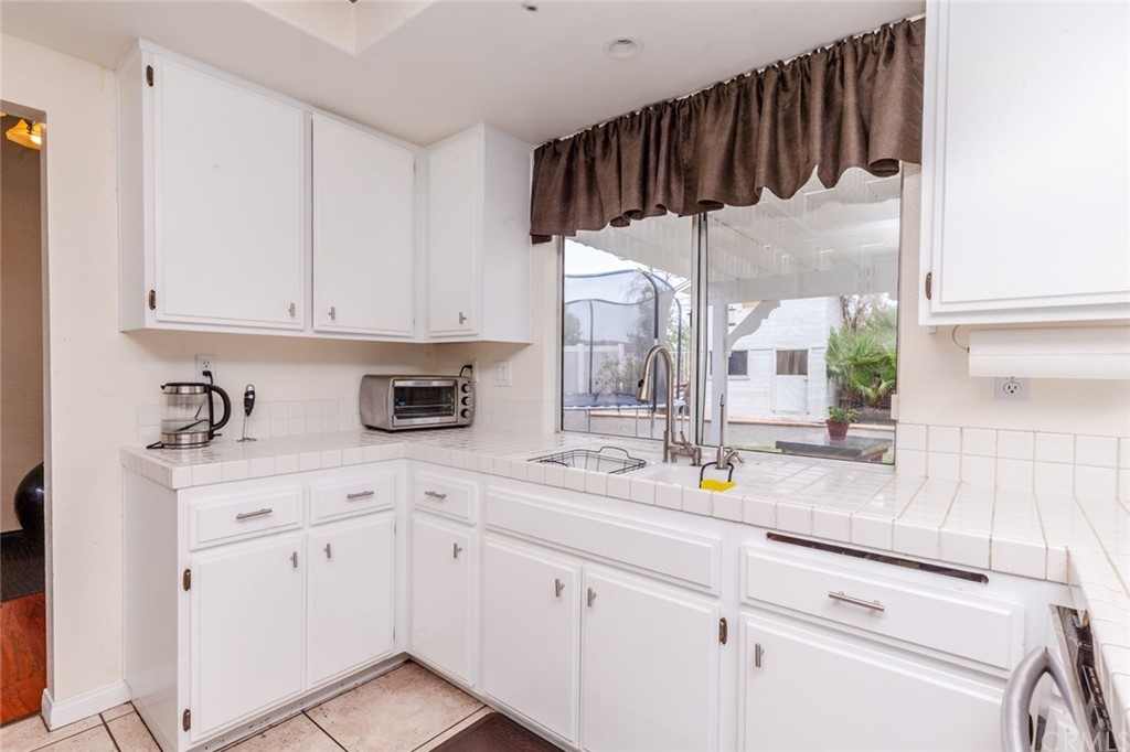 13058 Red Corral Drive Corona, CA 92883 - Photo 13 of 37 a kitchen with white cabinets and white appliances