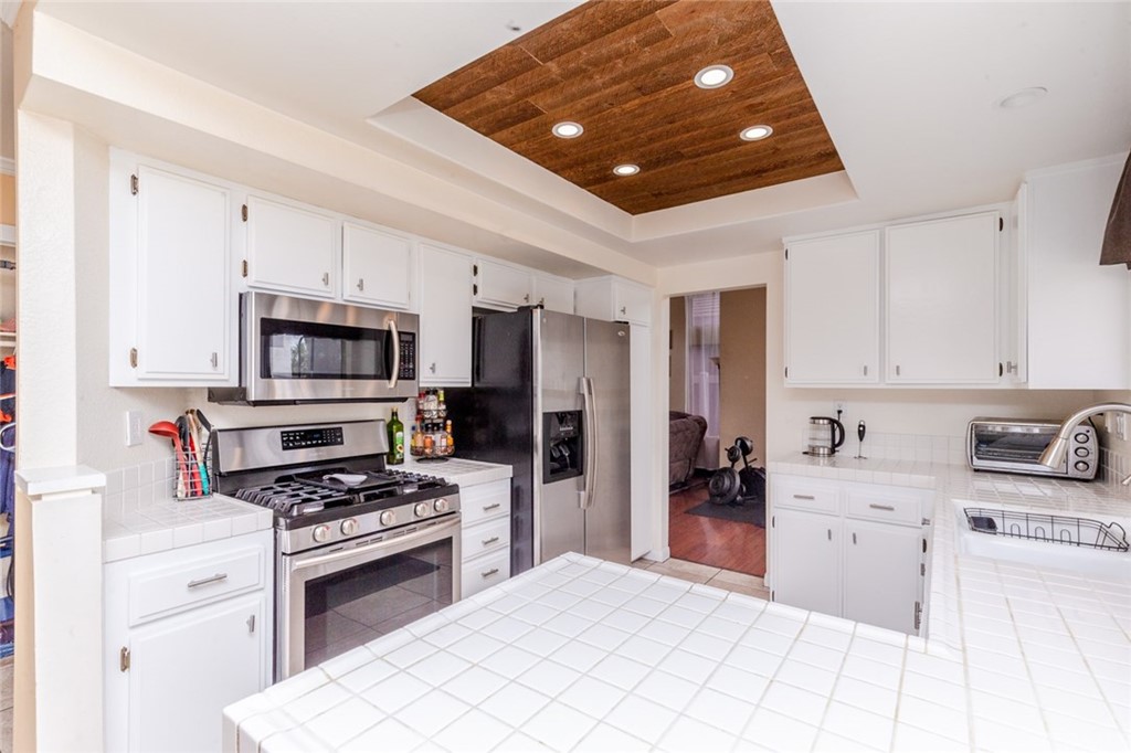 13058 Red Corral Drive Corona, CA 92883 - Photo 3 of 37 a kitchen with stainless steel appliances kitchen island granite countertop a stove sink and refrigerator
