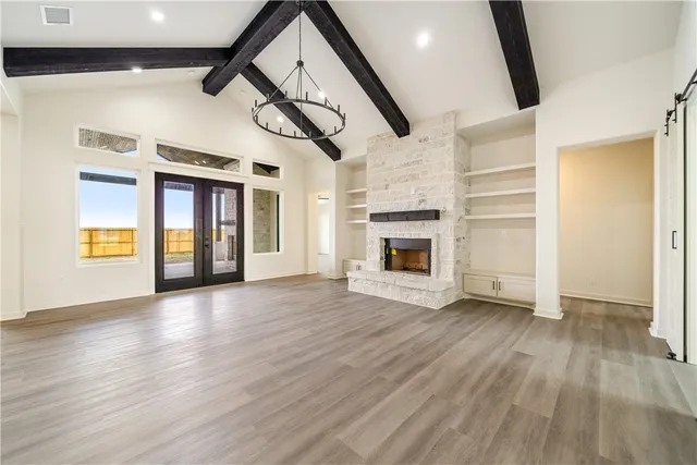 a view of an empty room with wooden floor fireplace and a window