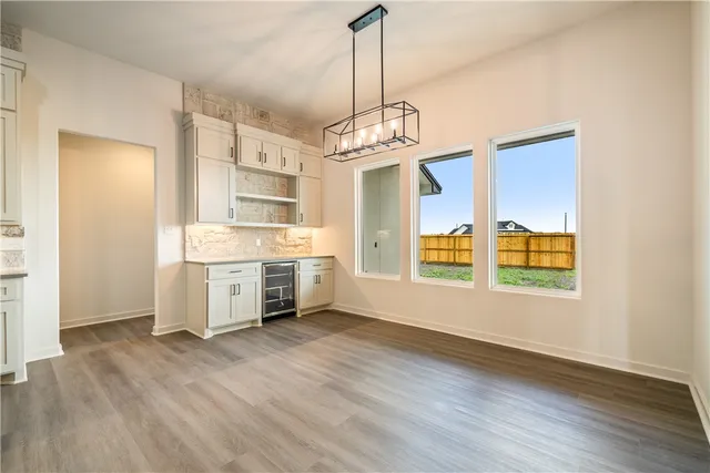 an empty room with wooden floor and a ceiling fan