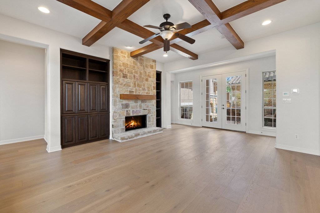 109 Largo Cove Austin, TX 78734 - Photo 15 of 40 A spacious great room featuring a cozy fireplace and elegant exposed beams, opening to outdoor living.