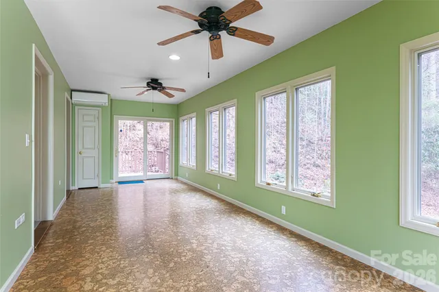 a view of an empty room with a window and a kitchen