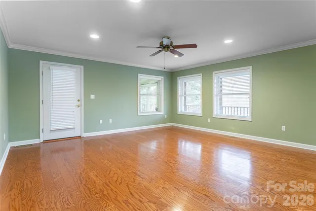 a view of an empty room with window and wooden floor