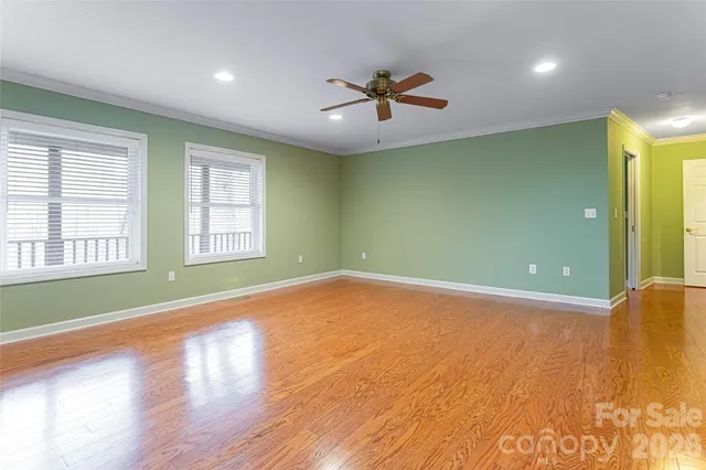 a view of an empty room with window and wooden floor