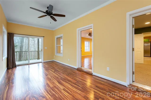 a view of empty room with wooden floor and fan