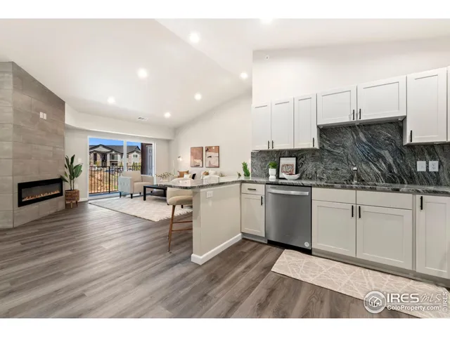 a kitchen with stainless steel appliances granite countertop a stove top oven a sink a dining table and chairs with wooden floor