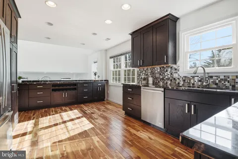 a kitchen with stainless steel appliances kitchen island granite countertop wooden cabinets and a stove