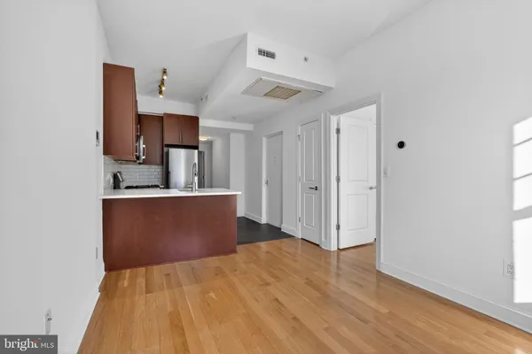 a view of kitchen and empty room with wooden floor