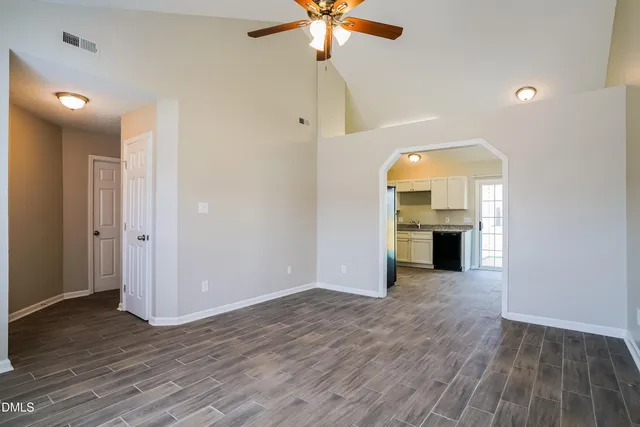a view of an empty room with a fireplace cabinet and wooden floor