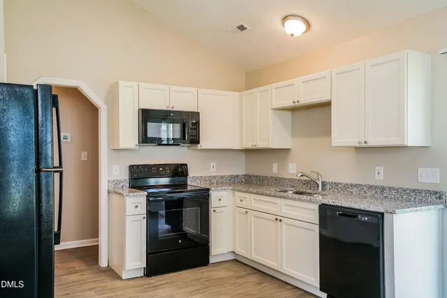 a kitchen with granite countertop white cabinets and stainless steel appliances